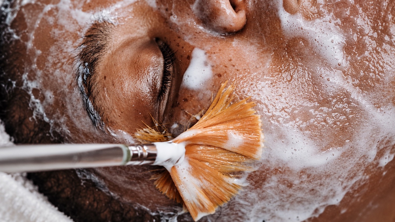 A fan brush applying cream during a facial